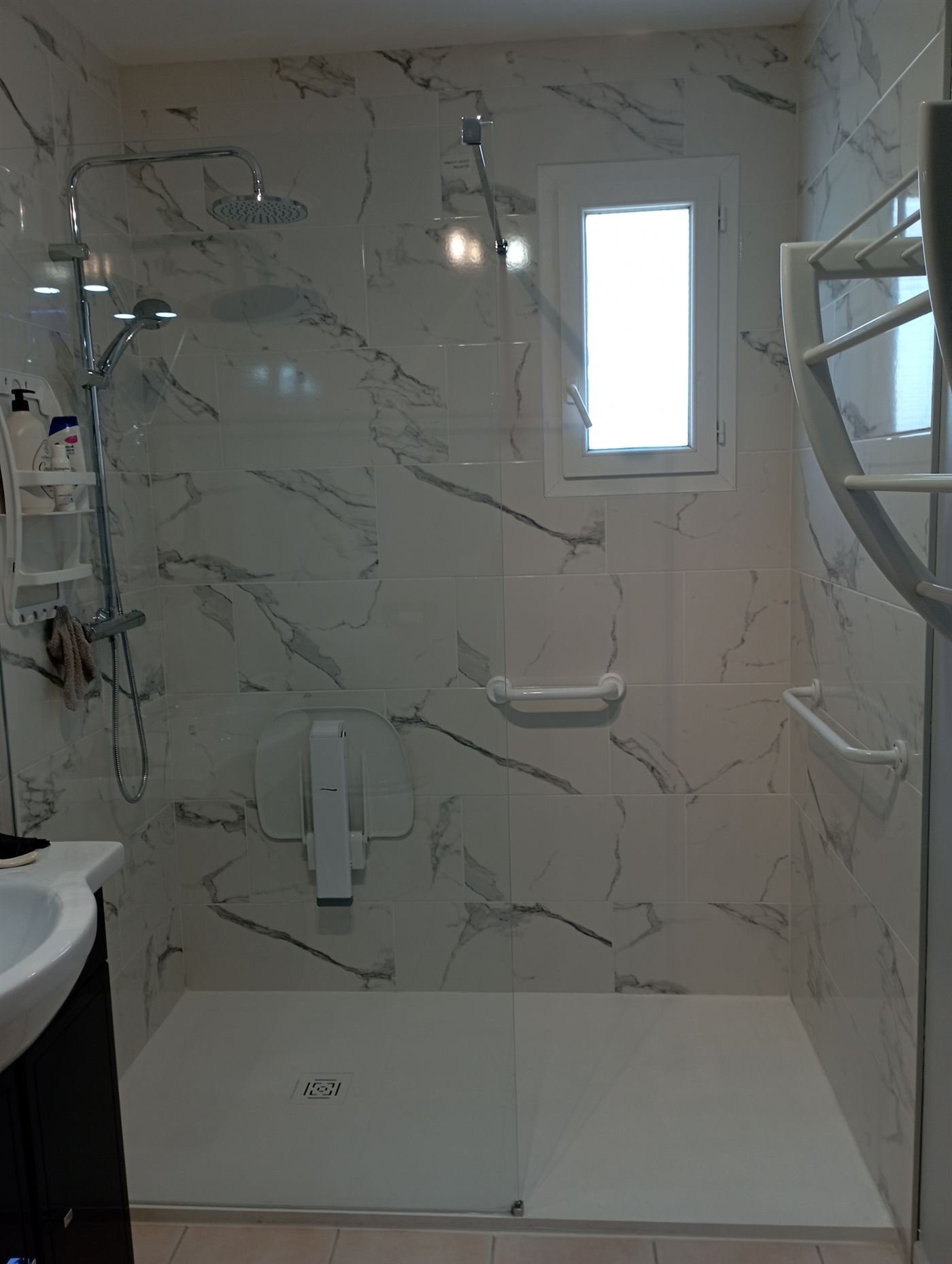 Douche à l'italienne adaptée avec siège de douche rabattable, barres d'appui et receveur extra-plat, réalisée dans le cadre d'un dossier MaPrimeAdapt'